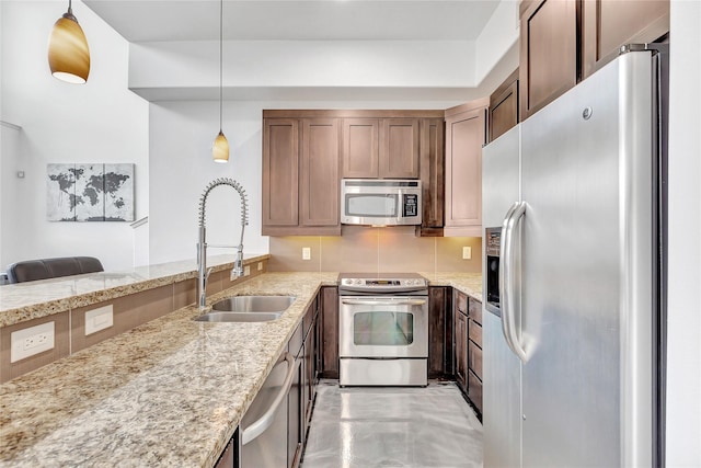 kitchen with light stone countertops, tasteful backsplash, appliances with stainless steel finishes, a sink, and hanging light fixtures