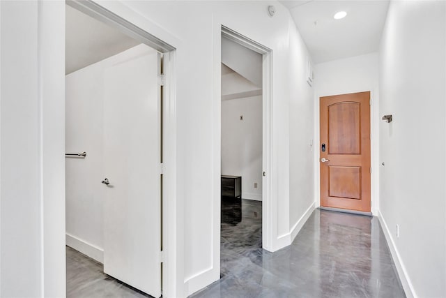 hallway featuring baseboards, finished concrete flooring, and recessed lighting