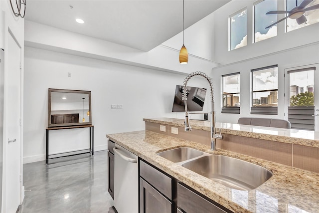 kitchen with a sink, pendant lighting, light stone countertops, dishwasher, and baseboards