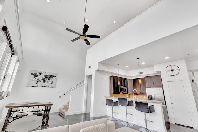 living room featuring stairs, ceiling fan, baseboards, a towering ceiling, and recessed lighting