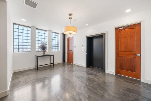 interior space with finished concrete flooring, visible vents, baseboards, recessed lighting, and elevator