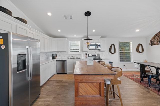 1731 Spur 458, Carmine, TX 78932 - kitchen with stainless steel appliances, a sink, wood finished floors, backsplash, and white cabinetry
