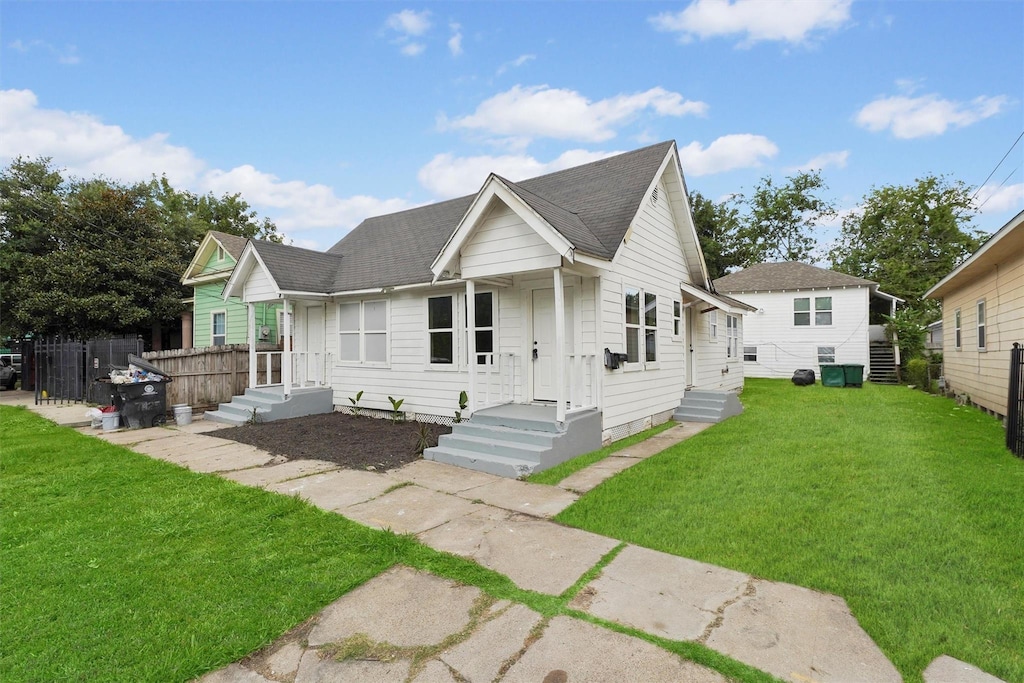 7425 Avenue Ave E, Houston, TX 77011 - view of front facade with a front yard, fence, and roof with shingles