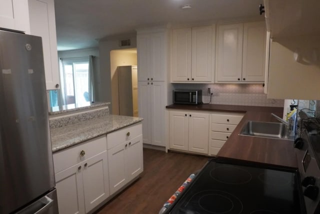 kitchen with dark wood finished floors, white cabinets, a sink, and stainless steel appliances