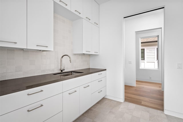 2215 Albans Rd, Houston, TX 77005 - kitchen featuring a sink, dark countertops, backsplash, baseboards, and white cabinets