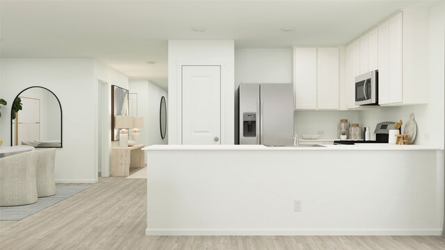 kitchen featuring appliances with stainless steel finishes, light wood finished floors, white cabinets, a peninsula, and baseboards