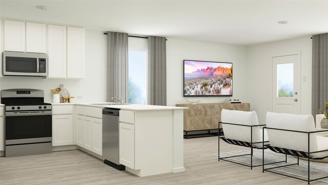 kitchen featuring stainless steel appliances, a peninsula, light wood-style floors, and a sink