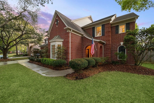 property exterior at dusk with a yard and brick siding