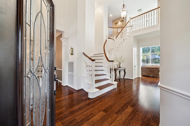 entrance foyer featuring hardwood / wood-style flooring, a high ceiling, baseboards, and stairs