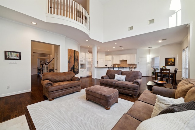 living room with visible vents, a towering ceiling, and stairway