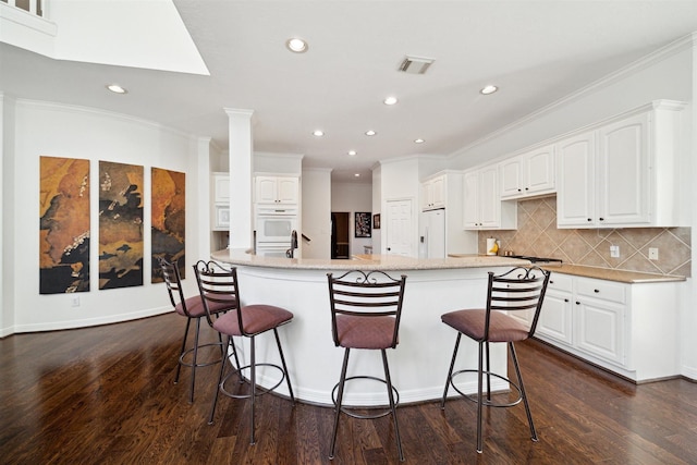kitchen with dark wood finished floors, a kitchen bar, visible vents, and recessed lighting