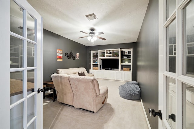living room with carpet, a textured ceiling, french doors, and a ceiling fan