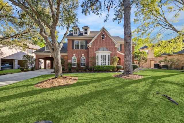georgian-style home featuring a front yard, brick siding, and driveway