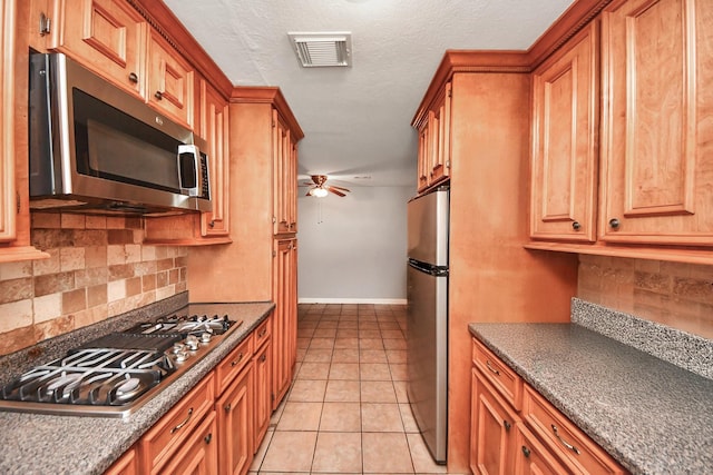 9926 Caffrey St, Houston, TX 77075 - kitchen featuring appliances with stainless steel finishes, ceiling fan, decorative backsplash, and brown cabinets