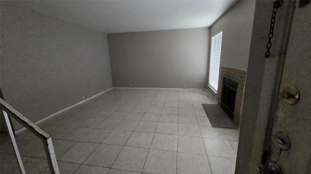 unfurnished living room with light tile patterned floors, a fireplace, and baseboards