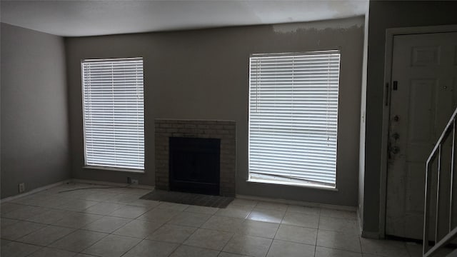 unfurnished living room with baseboards, tile patterned floors, and a fireplace