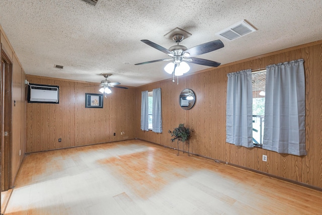 empty room with a textured ceiling, a wealth of natural light, visible vents, and wood finished floors