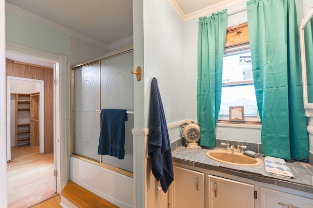 full bathroom with vanity, crown molding, combined bath / shower with glass door, and wood finished floors