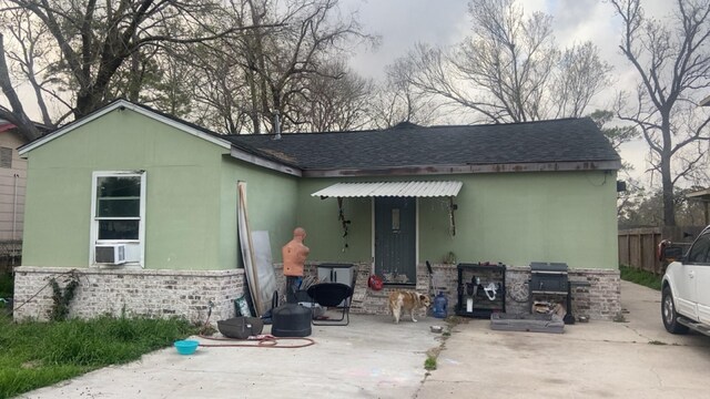 8145 Homewood Ln, Houston, TX 77028 - back of house featuring a patio area, area for grilling, roof with shingles, cooling unit, and stone siding