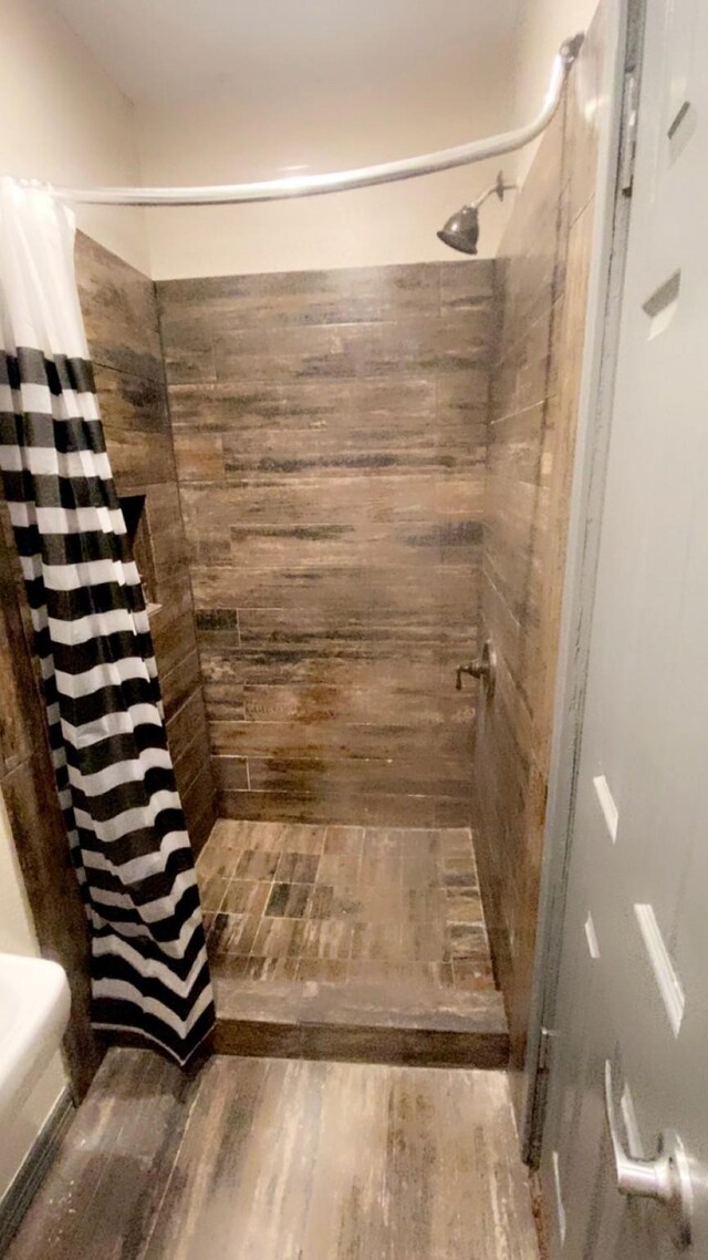 8145 Homewood Ln, Houston, TX 77028 - bathroom featuring a tile shower and wood finished floors