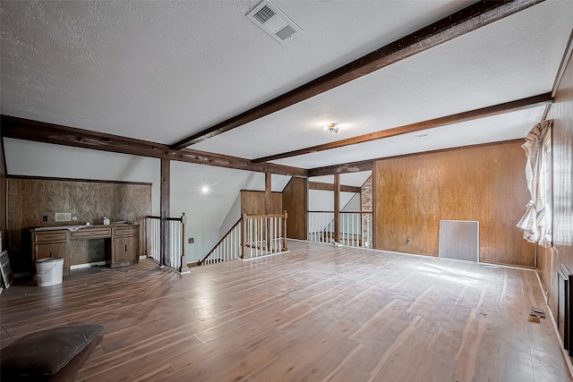 811 Loire Ln, Houston, TX 77090 - unfurnished living room with a textured ceiling, visible vents, beamed ceiling, and wood walls