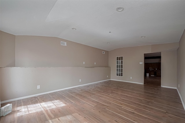 811 Loire Ln, Houston, TX 77090 - unfurnished room featuring visible vents, baseboards, lofted ceiling, and wood finished floors