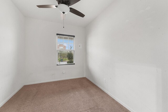 carpeted spare room featuring baseboards and ceiling fan