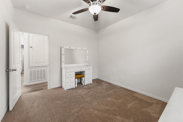 unfurnished office featuring carpet floors, baseboards, ceiling fan, and visible vents