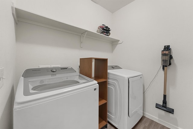 laundry room featuring baseboards, washing machine and dryer, dark wood-style flooring, and laundry area