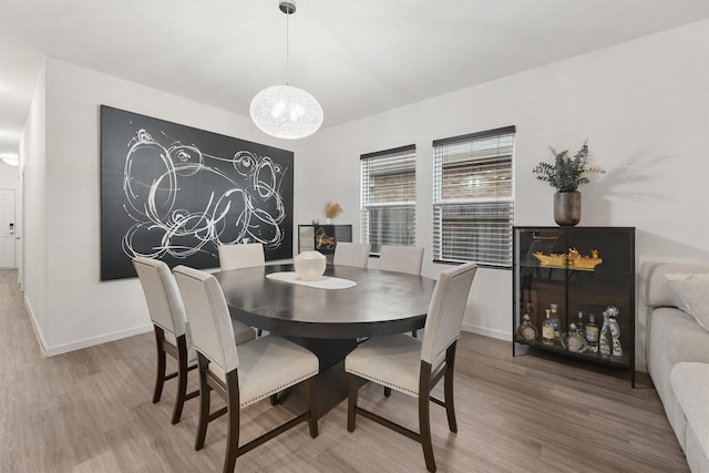 dining area with baseboards, a notable chandelier, and wood finished floors