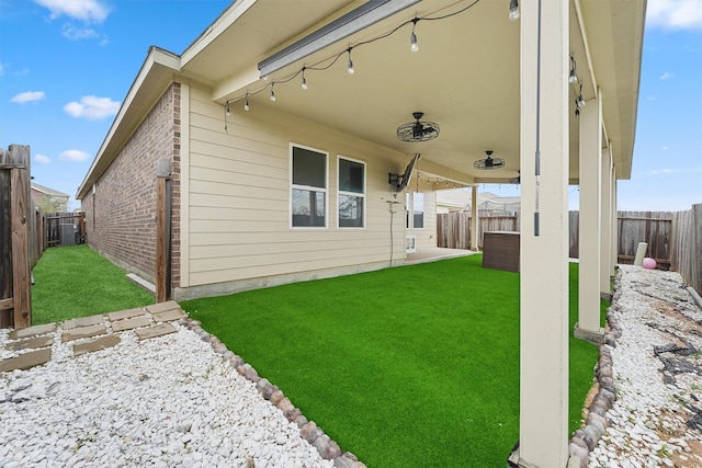 back of property with a fenced backyard, brick siding, a yard, and a patio