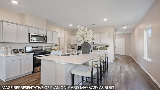 kitchen with an island with sink, light countertops, a breakfast bar area, stainless steel appliances, and a sink