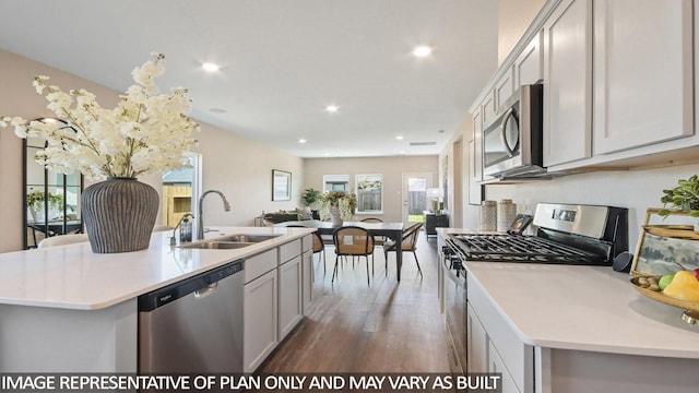 kitchen featuring open floor plan, light countertops, a kitchen island with sink, stainless steel appliances, and a sink