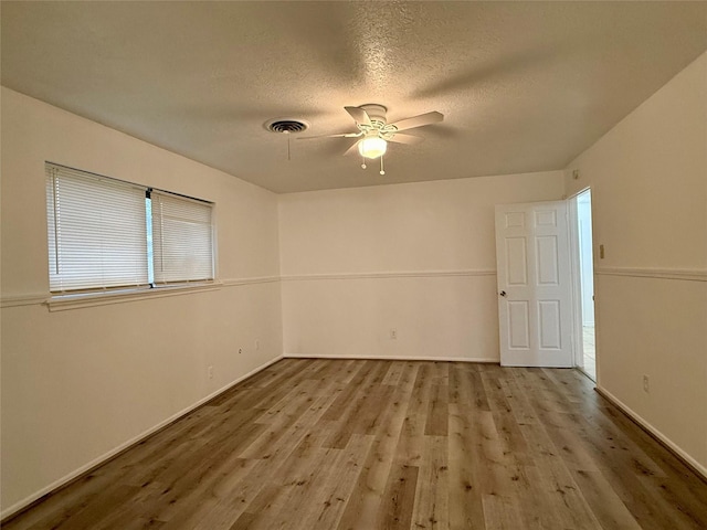 empty room with wood finished floors, visible vents, baseboards, a textured ceiling, and ceiling fan