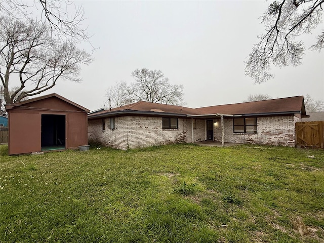 back of property with fence, a lawn, and a storage unit