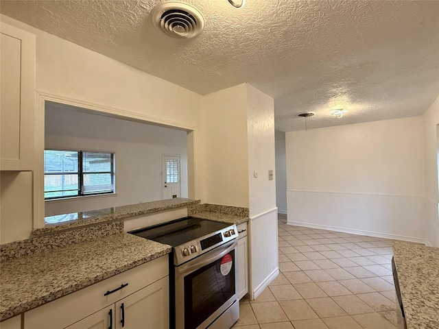 kitchen with light tile patterned floors, stainless steel electric range oven, visible vents, and a textured ceiling