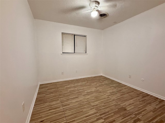 unfurnished room with baseboards, a ceiling fan, visible vents, and a textured ceiling