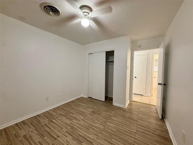 unfurnished bedroom featuring baseboards, a textured ceiling, and visible vents