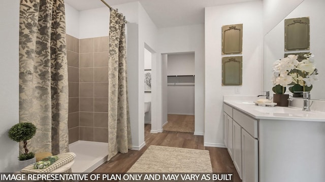 full bath featuring double vanity, a sink, a stall shower, and wood finished floors