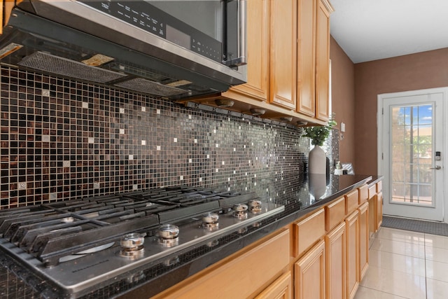 1906 Blue Water Bay Dr, Katy, TX 77494 - kitchen with stainless steel gas stovetop, decorative backsplash, light tile patterned flooring, dark countertops, and light brown cabinetry