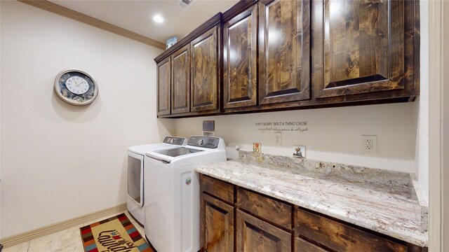washroom with baseboards, ornamental molding, tile patterned floors, washer and dryer, and cabinet space