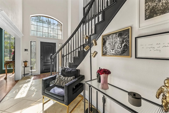 tiled entrance foyer featuring stairway, a high ceiling, and baseboards