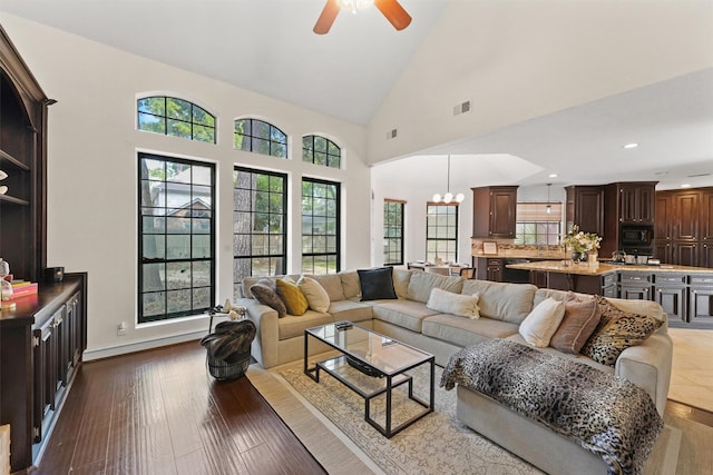 living area with dark wood-style flooring, visible vents, ceiling fan with notable chandelier, and a healthy amount of sunlight