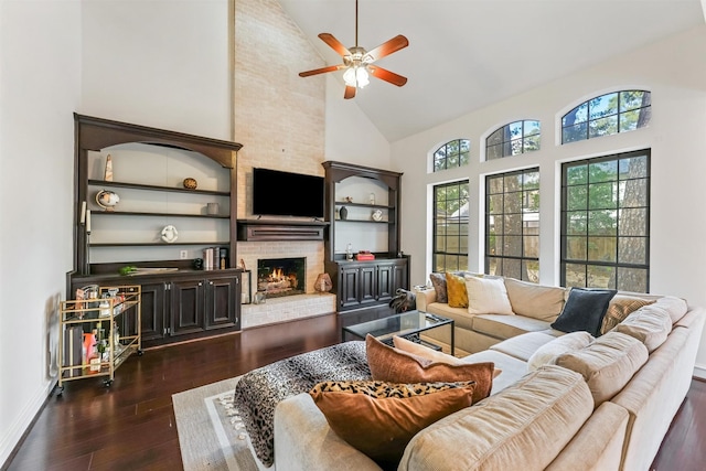 living room featuring baseboards, a fireplace, dark wood-style floors, ceiling fan, and high vaulted ceiling