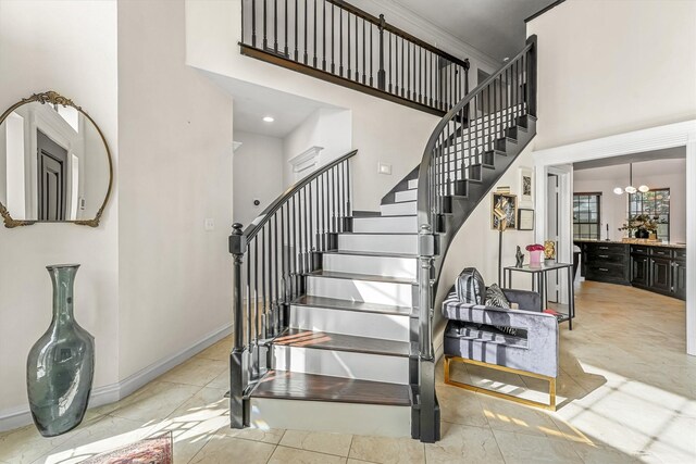 stairway featuring baseboards, a notable chandelier, and a towering ceiling