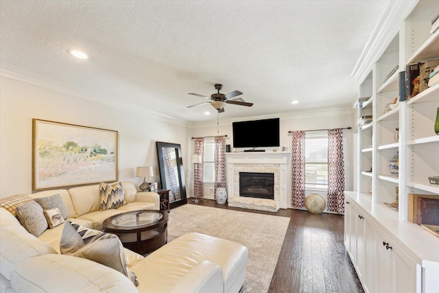 2688 Settlers Way Dr, Sealy, TX 77474 - living room with crown molding, a ceiling fan, a fireplace, a textured ceiling, and dark wood finished floors