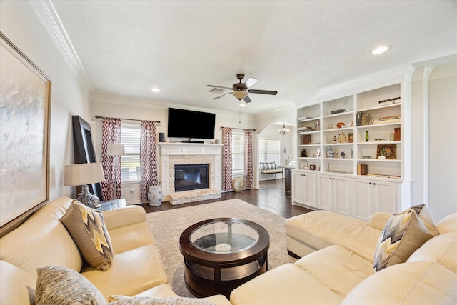 2688 Settlers Way Dr, Sealy, TX 77474 - living area with crown molding, dark wood-style flooring, a textured ceiling, ceiling fan, and a stone fireplace