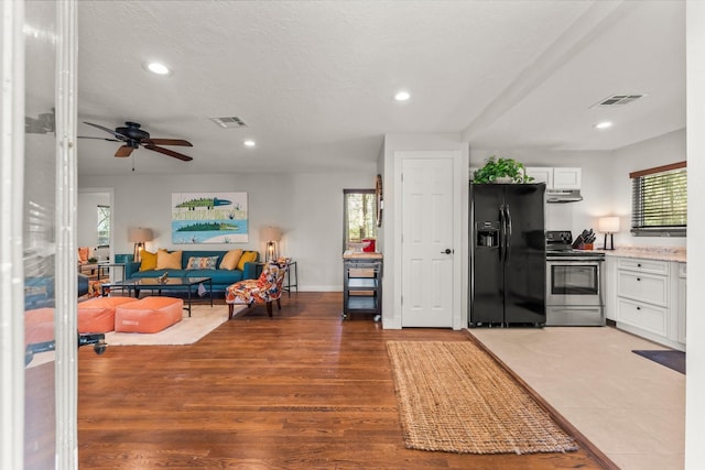 kitchen with black fridge with ice dispenser, electric stove, visible vents, and under cabinet range hood