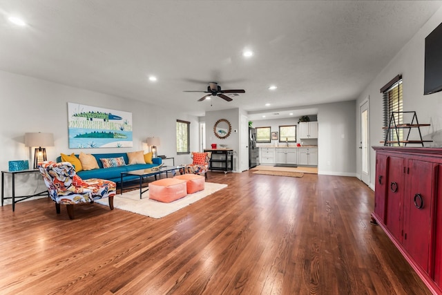 living room featuring a ceiling fan, recessed lighting, baseboards, and wood finished floors