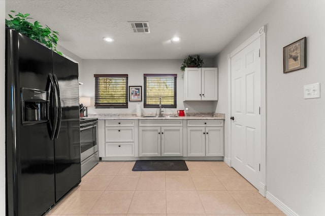 kitchen with light tile patterned flooring, visible vents, a sink, black fridge, and electric range